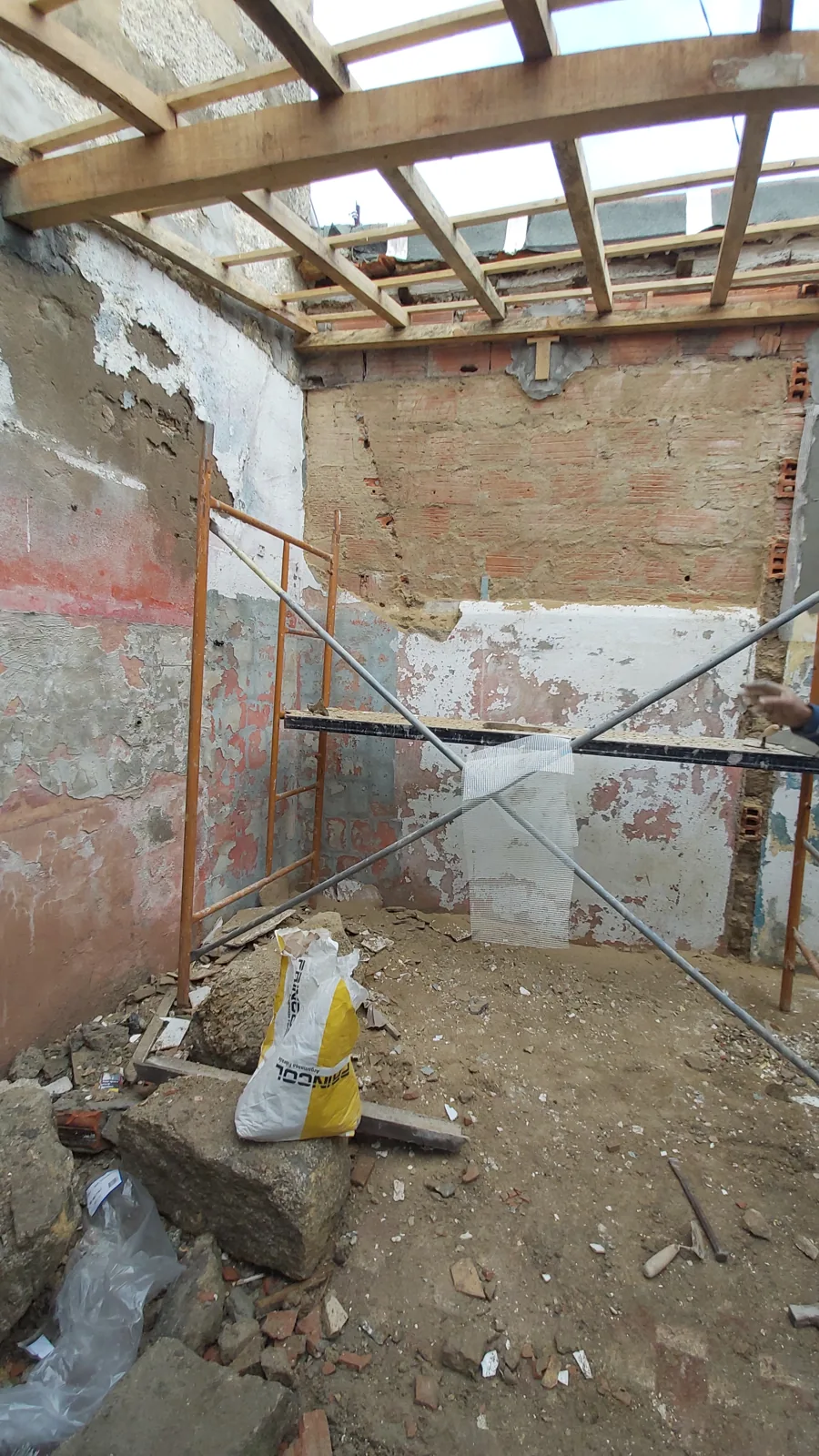 Interior da casa antes da renovação, com paredes e cobertura expostas