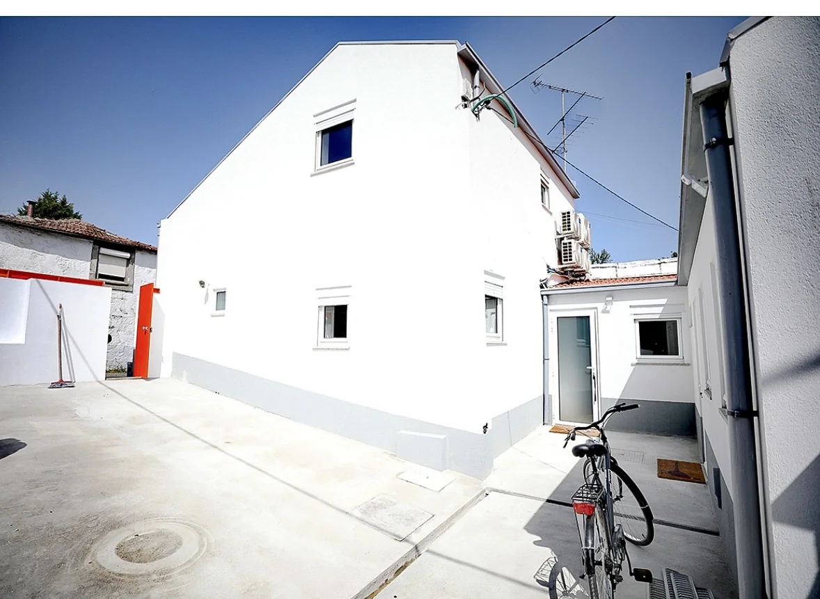 Fachada interior renovada, com pintura branca e cinzenta e pátio