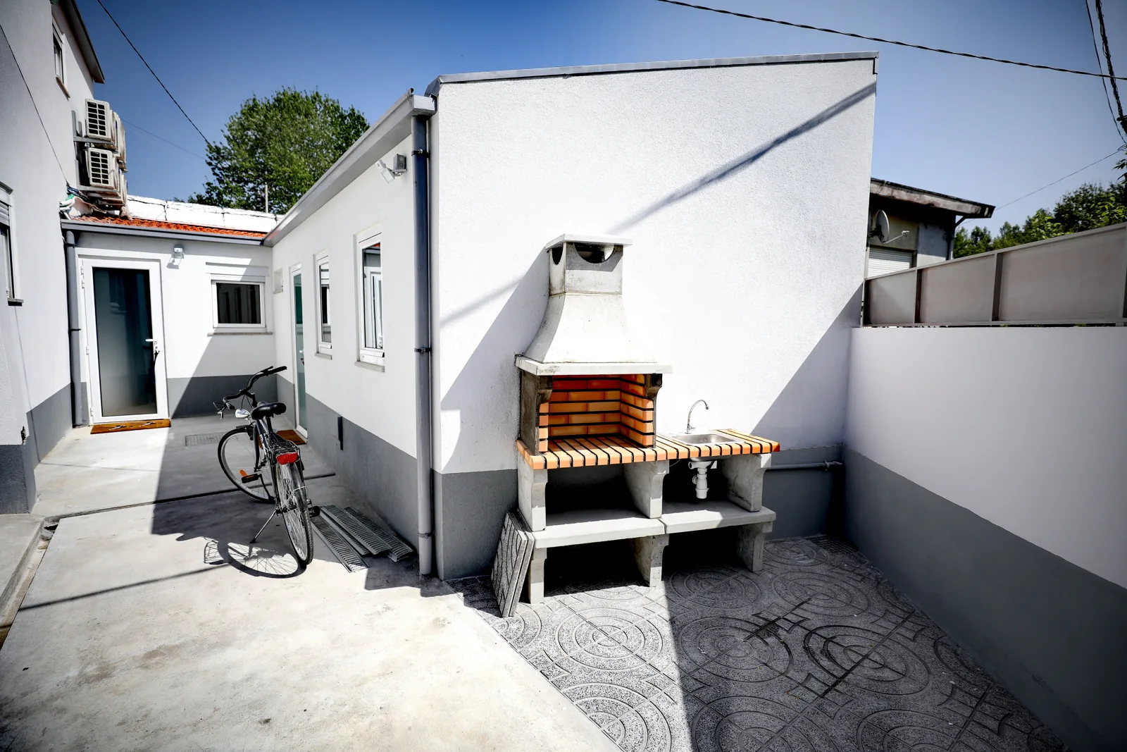 Pátio recuperado da Casa Campanhã, com churrasqueira e fachada branca