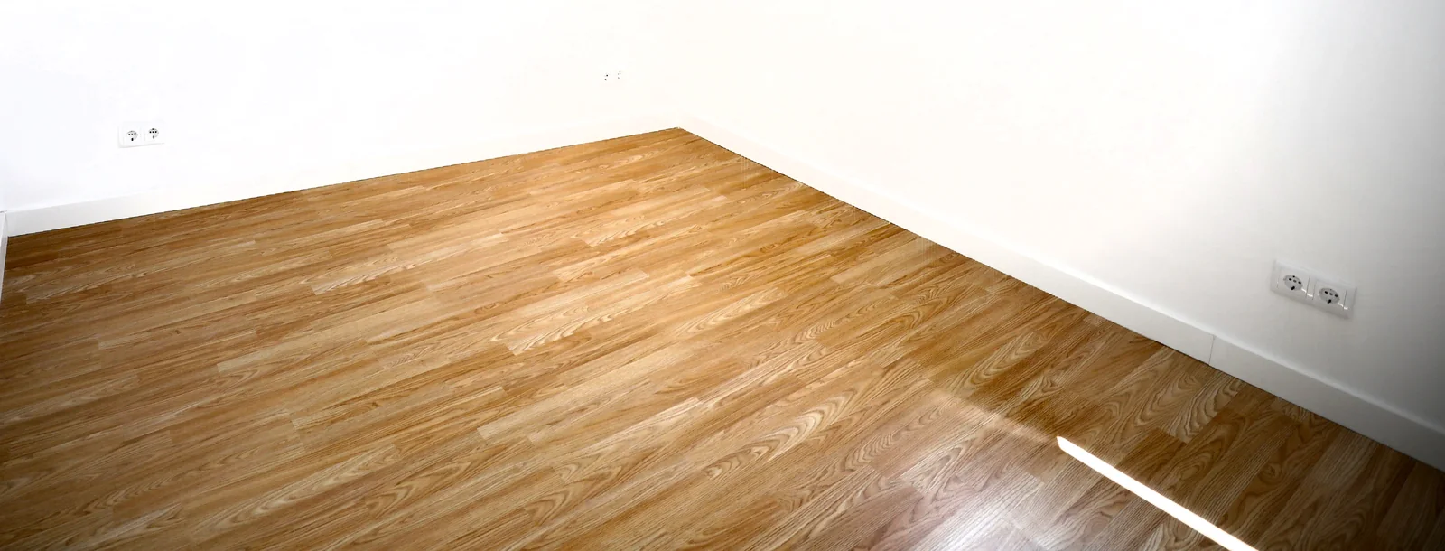 Pavimento com acabamento de madeira e rodapés brancos junto às paredes pintadas